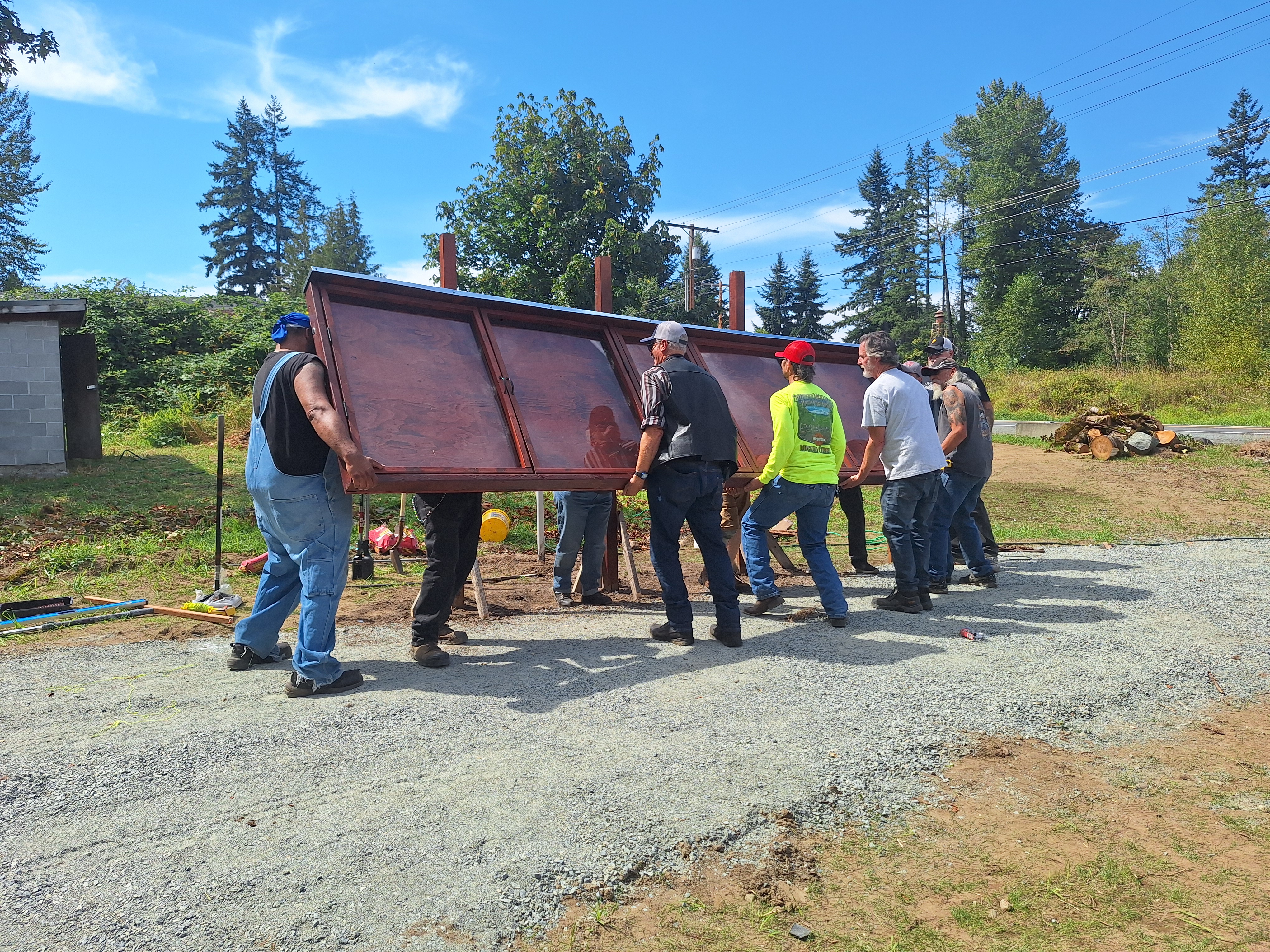 Volunteers lifting a large wooden memorial panel together